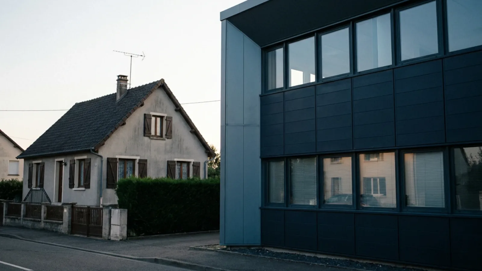 Maison de famille et bâtiment d'entreprise voisins, illustrant le choix entre transmission familiale et cession