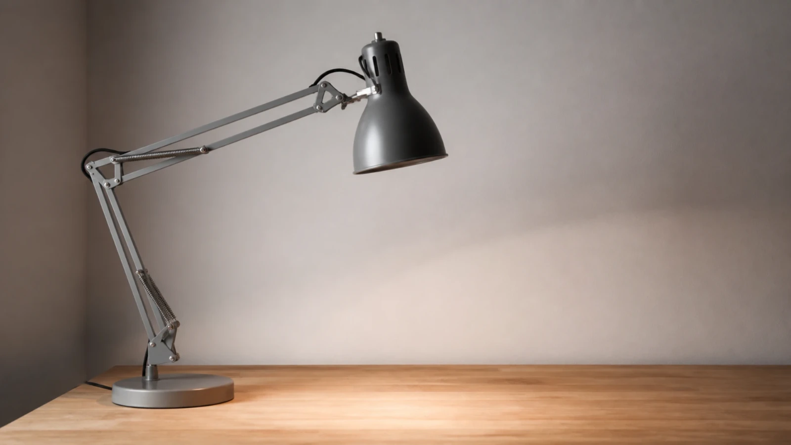 Lampe d’architecte articulée éteinte au-dessus d’une table de travail vide